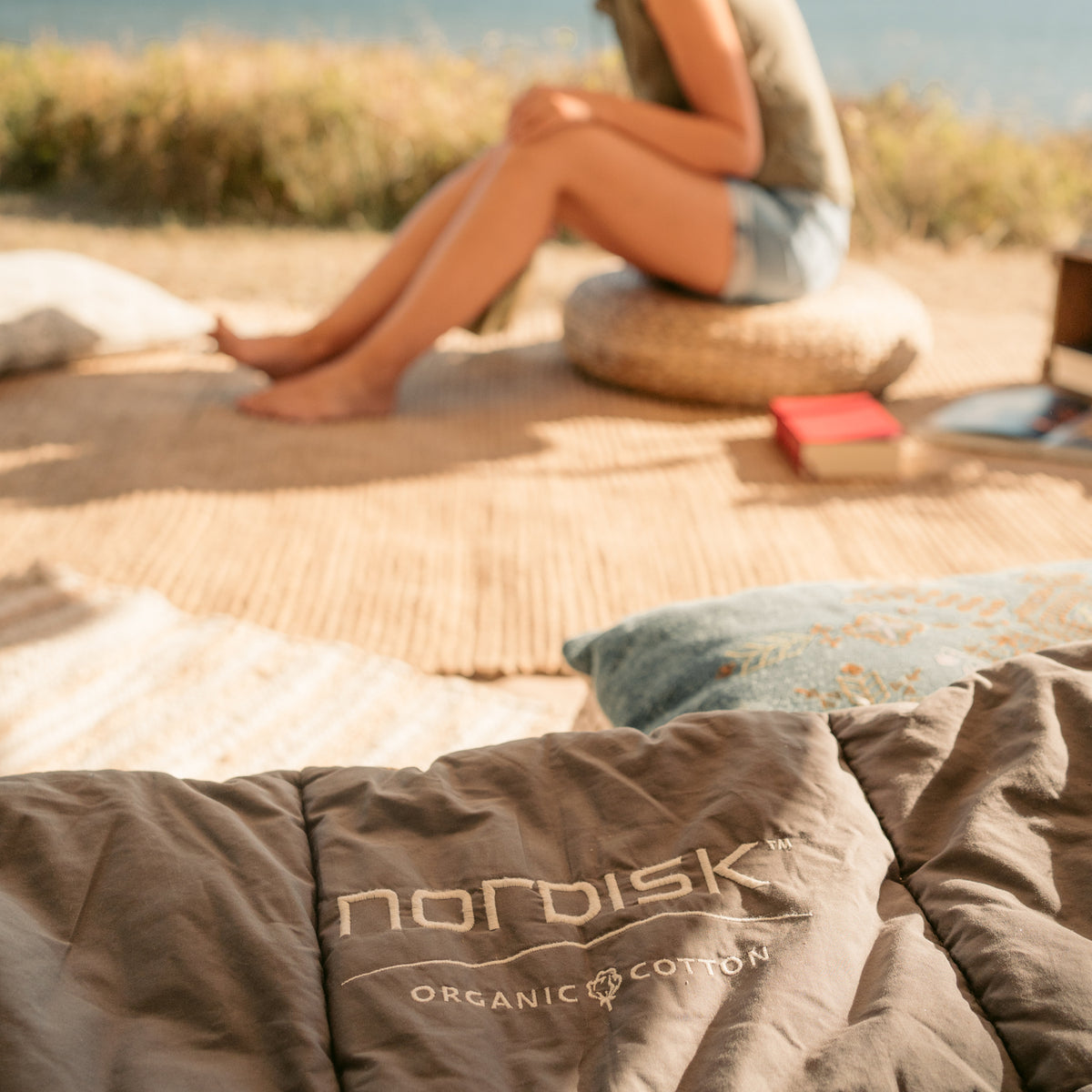 Nordisk organic cotton sleeping bag in a cozy glamping outdoor setting with a woman.